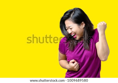 Exuberant exultant young Chinese woman cheering a victory, success or win punching the air with her fists and laughing over candy background with copy space