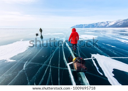 Woman with a sledge walk is on the ice of Lake Baikal. Royalty-Free Stock Photo #1009695718