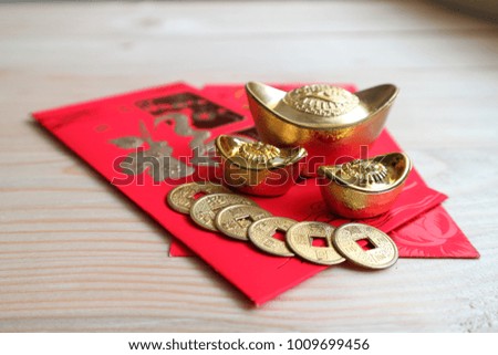 Gold and money coin on red pocket " Ang Pao" with background wood table, Chinese word mean "Happy"