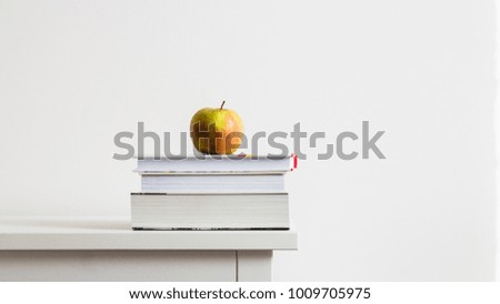 Education concept. Books and apple on a white wooden table isolated on white background