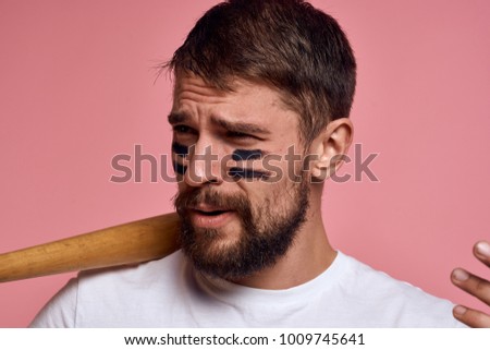 man with stripes on his face in his hand baseball bat on a pink background                               