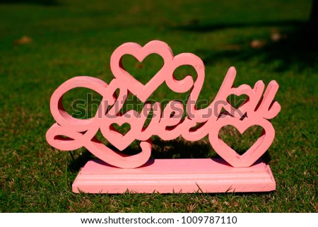 I love you sign hand made from wood paint in pink on green grass