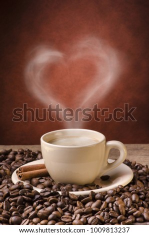 rustic wooden table with coffee beans and a cup of hot coffee from which steam exits forming a heart