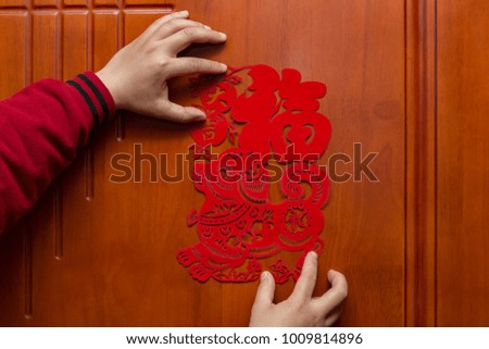 man sticking a Chinese New Year of the Dog 2018 to a door the Chinese means good luck