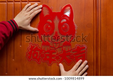 man sticking a Chinese New Year of the Dog 2018 to a door the Chinese means good luck for the Year of Dog