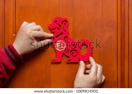 man sticking a Chinese New Year of the Dog 2018 to a door the Chinese means prosperous
