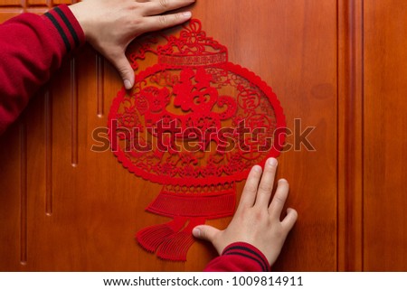 man sticking a Chinese New Year of the Dog 2018 to a door the Chinese means fortune and family