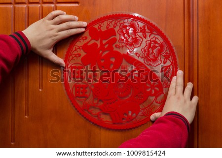 man sticking a Chinese New Year of the Dog 2018 to a door the Chinese means fortune and year of the Dog