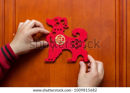 man sticking a Chinese New Year of the Dog 2018 to a door the Chinese means prosperous