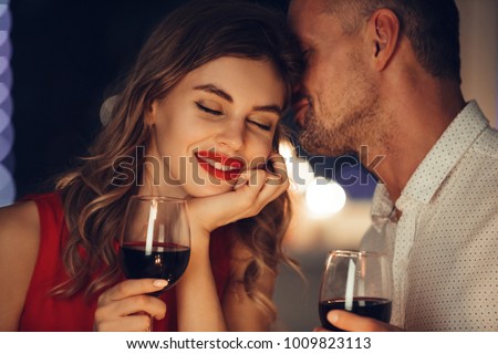 Young handsome man whisper to his gorgeous woman while have romantic dinner and drinking wine on valentines day Royalty-Free Stock Photo #1009823113