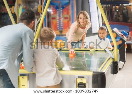 happy family playing air hockey together in entertainment center   Royalty-Free Stock Photo #1009832749