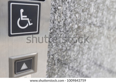 black and white sign button on silver elevator front wall with blur background.That symbol mean for disable person and up.concept rights for disabled person