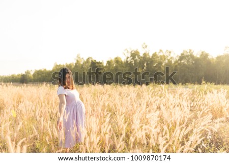 Portrait of pregnant woman on the field,Asian woman hold grass flower on sunset