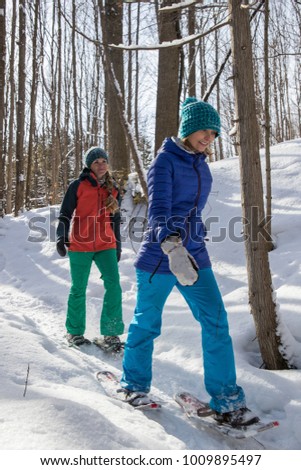 Pair of female friends snowshoeing in forest in Ontario, Canada.