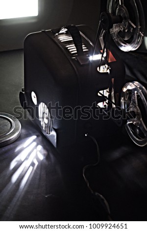Old film projector and a glowing screen in the dark