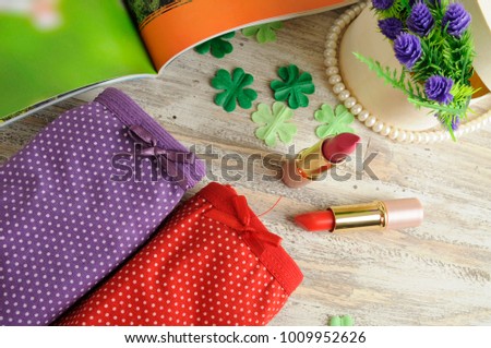 fashion  lipsticks with decorative flowers ,underpants and necklaces on table 