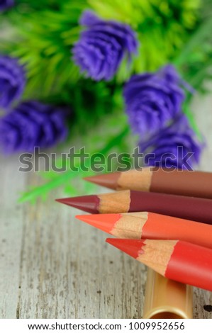 Colorful  lip pencils with flowers on the table