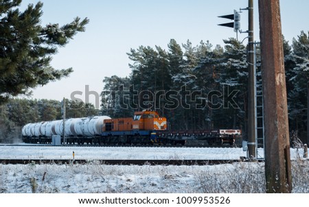 Freight train with cisterns coming through winter forest. Ventspils, Latvia Royalty-Free Stock Photo #1009953526