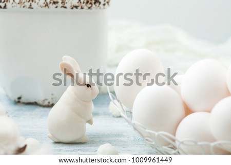 Easter white eggs and a rabbit on a light background Background for a postcard.