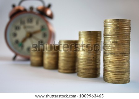 Rows coin in fount of alarm clock on the white background for business concept,finance,tax time  for currency and financial business investment, loans to planned investment. Time is money. 