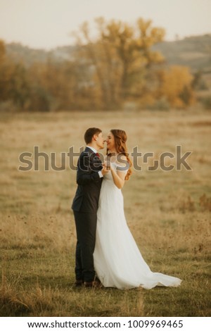 Beautiful bride and groom standing in grass and kissing. Wedding couple fashion shoot