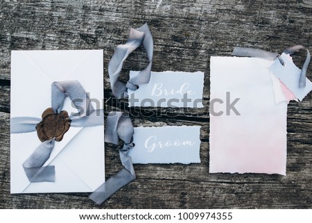 Beautiful wedding attributes in pastel colors. Invitation, envelope, bride and groom. Wooden background. Top view