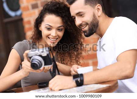 Portrait of a couple sitting down at a cafe and looking  photos