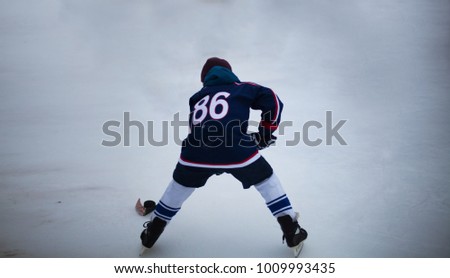 Child hockey player with hockey stick and puck on natural ice Royalty-Free Stock Photo #1009993435