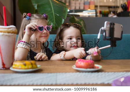 Two cute little girls making selfie in cafe