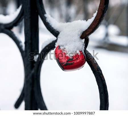 Wedding castle in the form of heart shape, attached to the fencing of the river bridge in winter time