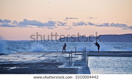 Couple Playing ande taking pictures near the surf, Sea Baths, Newcastle Australia