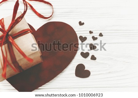 happy valentine's day concept. stylish present box and velvet hearts on white wooden rustic background in light. valentines day. greeting card with space for text. wedding  accessories