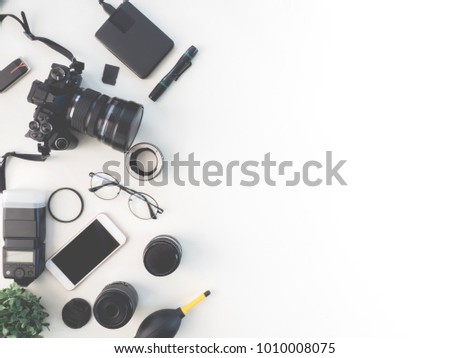 top view of photographer concept with digital camera, memory card, external harddisk, flash and camera accessory on white background with copy space.