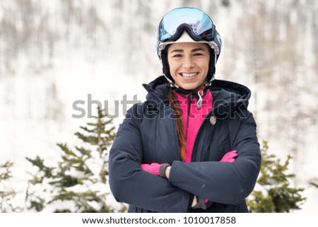 Portrait of a smiling skier on vacation in the mountains, behind her you can see the snow-covered mountain. Concept of: holidays, sport, passion, mountain.
