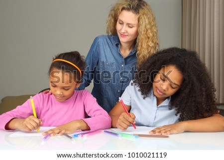 mom watches as her daughter drawing with crayons