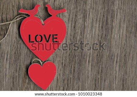 Two Red shape hearts with two pigeons on wooden background. Love text on heart pendant.Copy space for greeting.