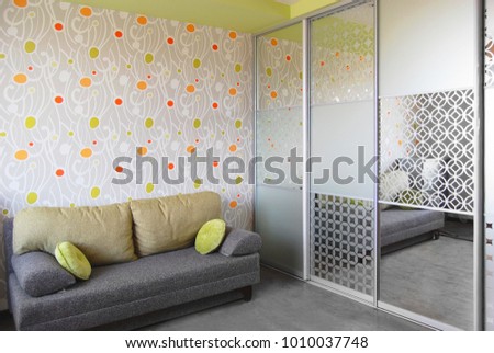 part of the interior, children's room, mirrored wardrobe, picture on the mirror, sofa in the room, bright wallpaper, orange-green color scheme