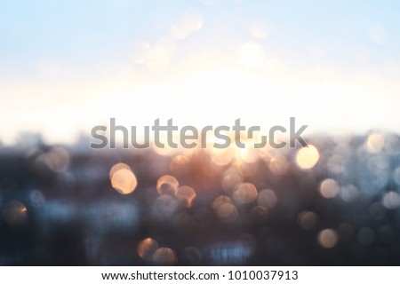 Rain drops texture on window glass with stunning vintage blue violet sunset light abstract blurred cityscape skyline bokeh background. Soft focus