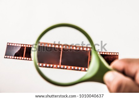 Film strip with magnifying glass isolated on white background