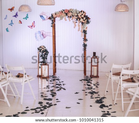 Arch on wedding decorated with flowers. Large candlesticks with candles in the room with decor. Wedding ceremony