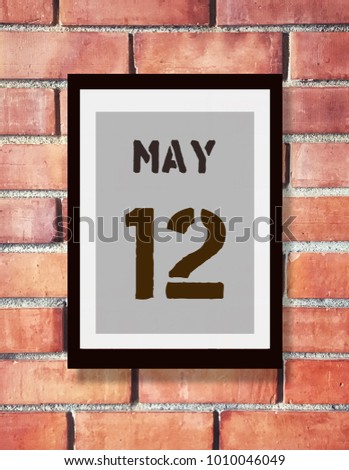 May 12th. 12 May calendar on the wood photo frame with brown brick background. Spring day