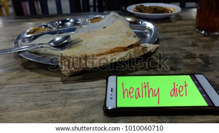 Breakfast with thosai, Mutton Curry and sugar free tea with illuminated mobile phone. Is a mixture of calories and healthy diet.