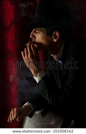 Man with hat standing in profile and smoking in darkness