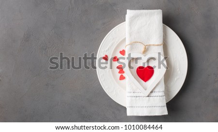 Valentines day meal background with white wood vintage heart  and red candy hearts, white plate and napkin. Romantic holiday table setting. Concrete background with blank. Restaurant concept. Flat lay