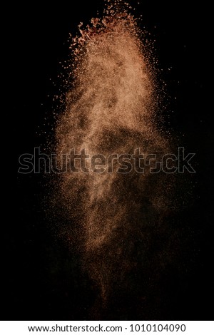 Cocoa powder explosion in motion. Chocolate dust on a black background. Action food photography.