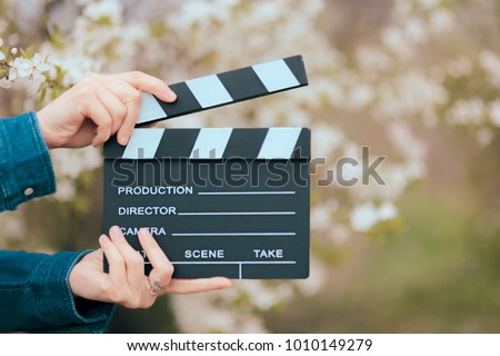 Hands Holding Film Slate Cinema Clapper on Spring Blooming Background. Film making  video shooting production outdoors footage concept image 
 Royalty-Free Stock Photo #1010149279