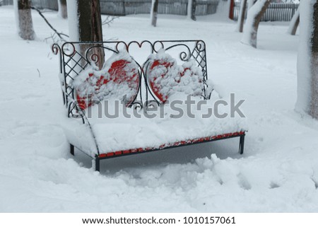 A photo of a bench in a winter park. An empty, lonely bench marked by a snowdrift.