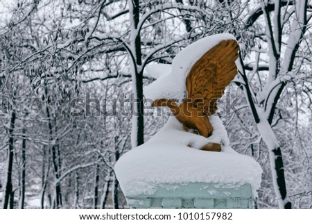 Park sculpture in winter. Photo of a bronze eagle with snow