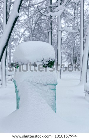 Park sculpture in winter. Photo of a flowerpot on a high pedestal covered with snow