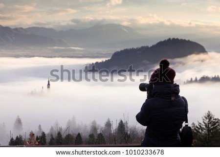 photographer woman taking pictures of amazing sunrise at lake Bled from Ojstrica viewpoint, Slovenia, Europe - travel background